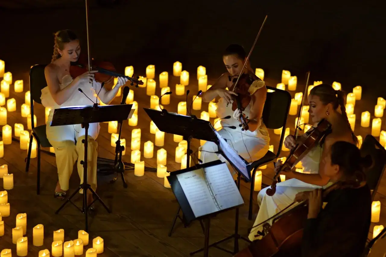 Koncert skrzypcowy przy świecach w Poznaniu. Muzycy w białych strojach tworzą magiczną atmosferę.