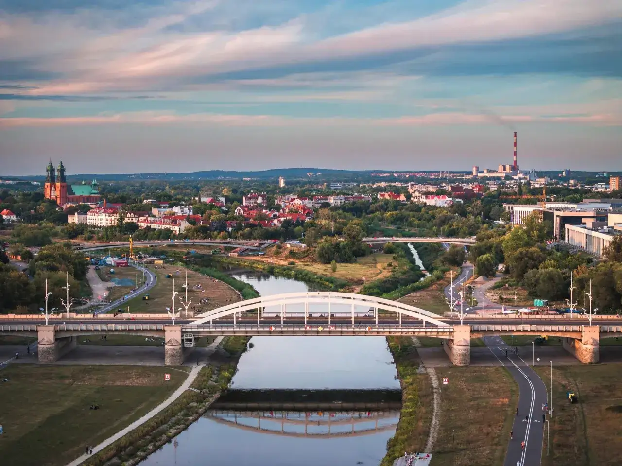 Widok na Poznań z mostami berdychowskimi, rzeką Wartą i katedrą w tle.