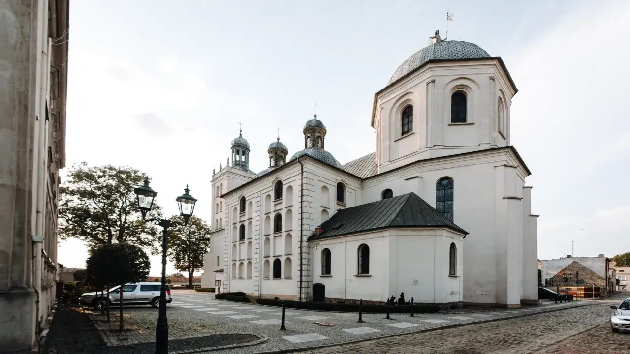 Majestatyczna fara w Grodzisku Wlkp. z charakterystycznymi kopułami i wieżami, oświetlona łagodnym światłem.